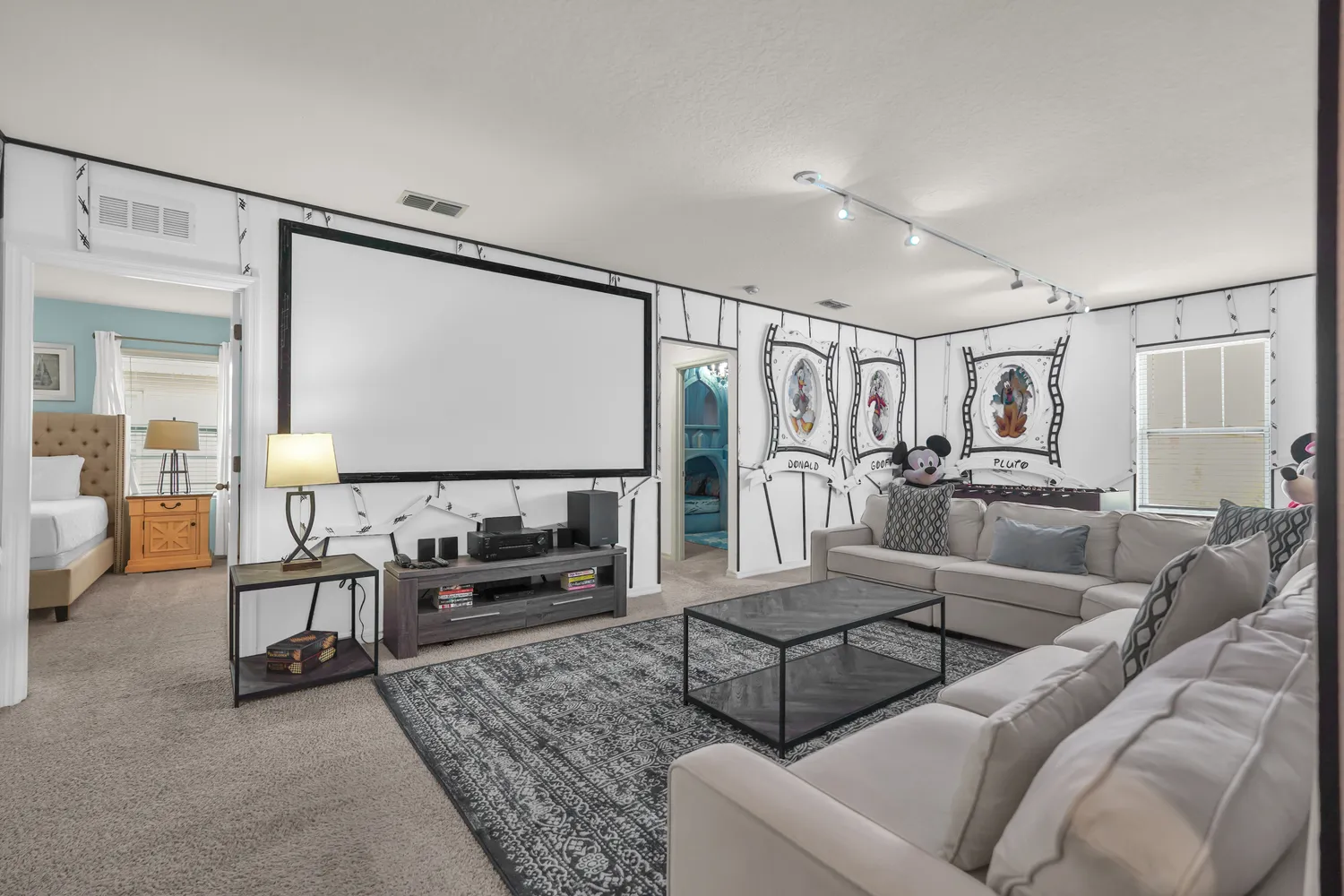 Disney-themed home theater room with projector screen, sectional sofa, and character wall art
