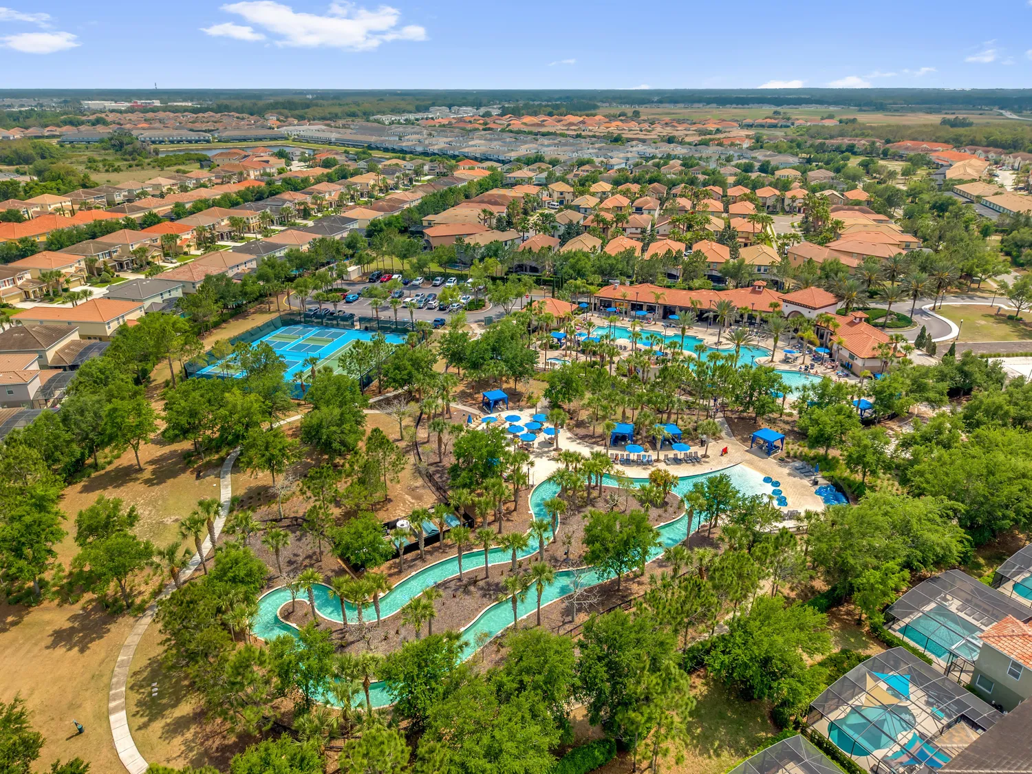 Aerial view of resort community pool complex with lazy river, water park, and tropical landscaping