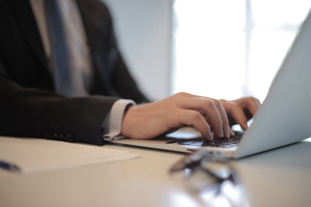 a-businessman-typing-on-a-laptop-at-a-desk-with-a-blurred-background