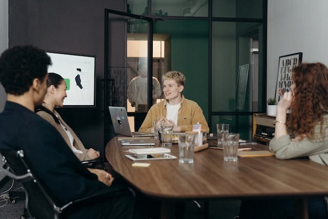a-group-of-people-in-a-conference-room-having-a-meeting-around-a-wooden-table