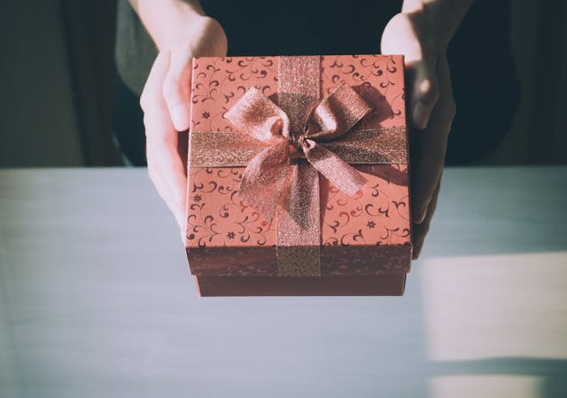 hands-holding-a-decorative-red-gift-box-with-a-bow