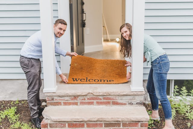smiling-couple-placing-a-welcome-doormat-at-the-entrance-of-their-new-home